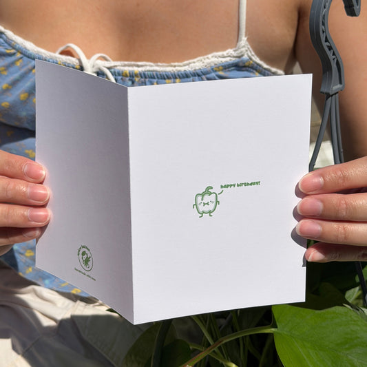 Person holding a birthday card with a paprika character saying happy birthday