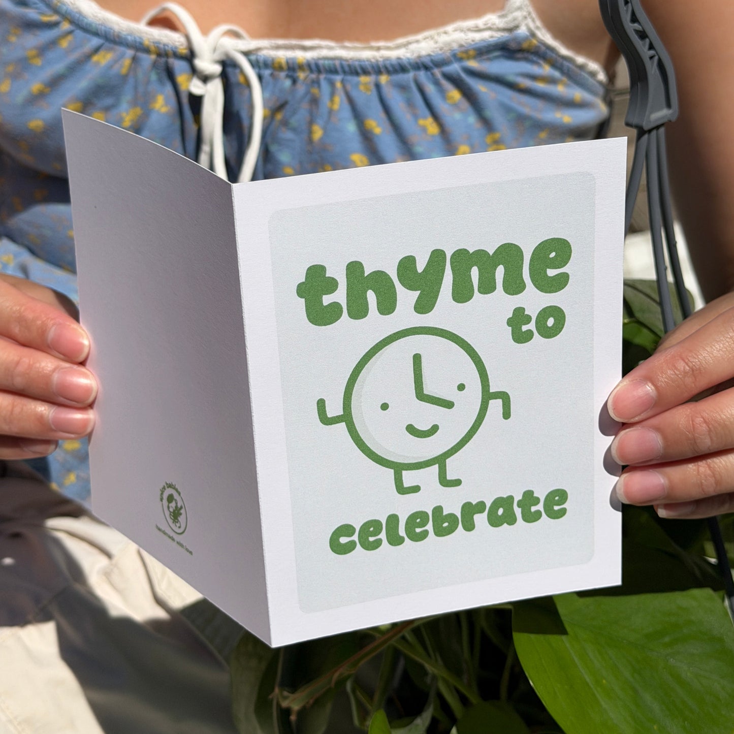 Person holding a birthdaycard with 'thyme to celebrate' text and spice baby