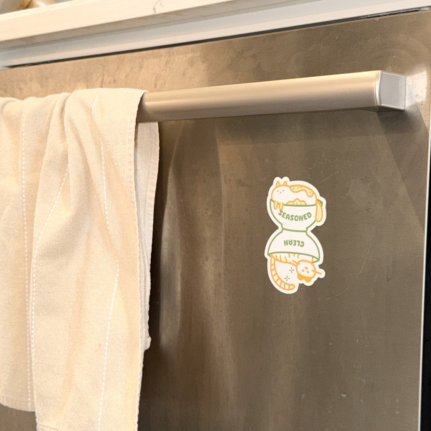 Beige towel hanging on a dishwasher with a dishwasher magnet