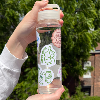 Clear water bottle with stickers held by a person outdoors