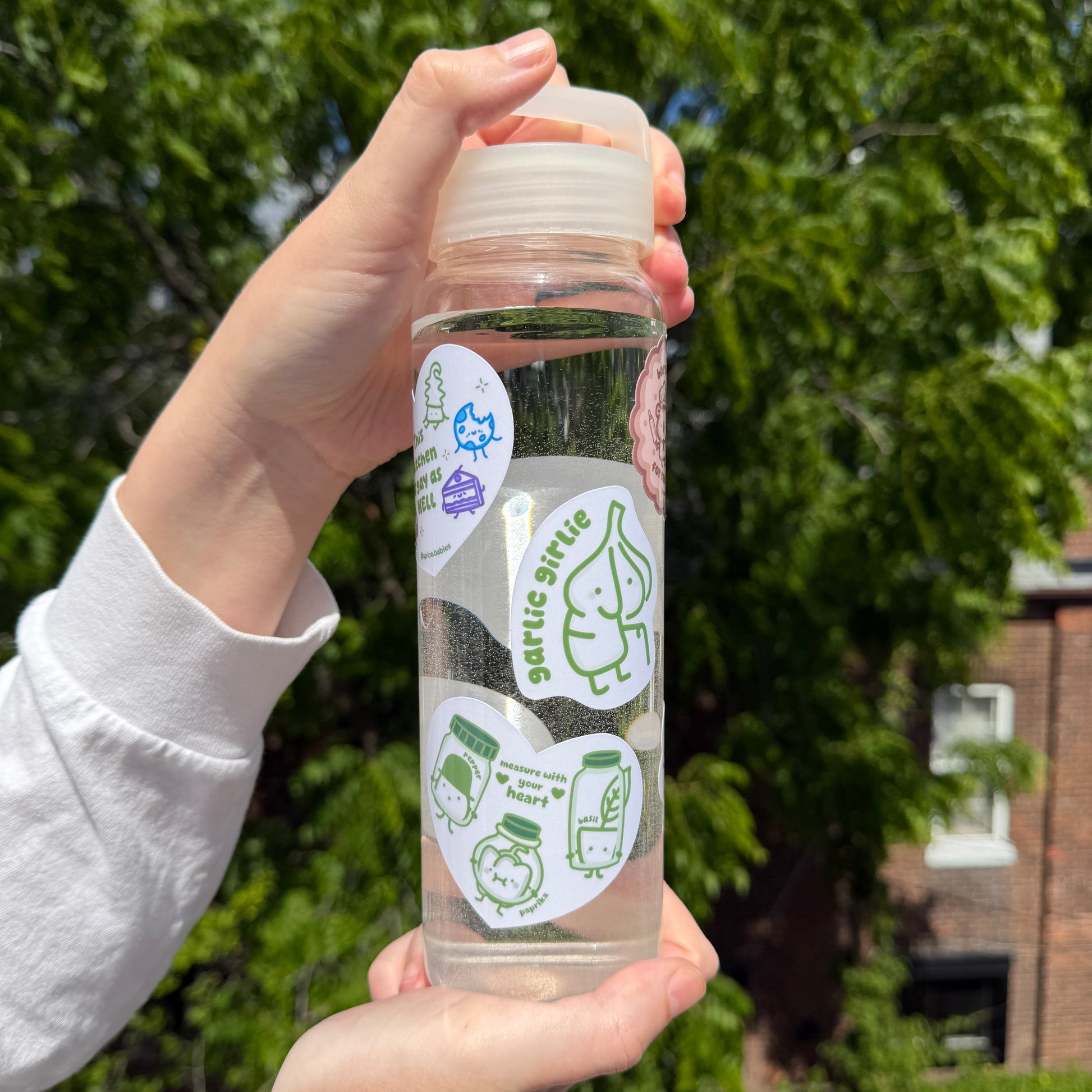 Clear water bottle with green labels held by a person outdoors